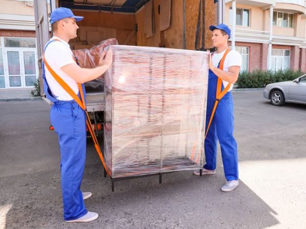 Due operai per il ritiro mobili usati mettono una dispensa usata nel furgone